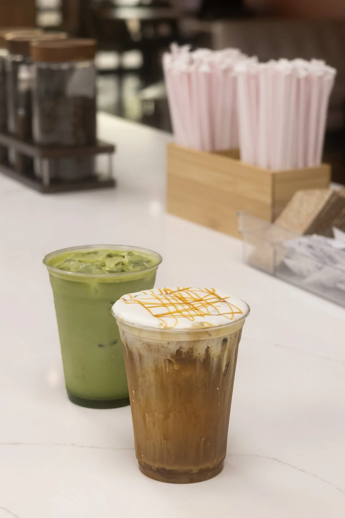 A green matcha drink alongside an iced coffee topped with cream